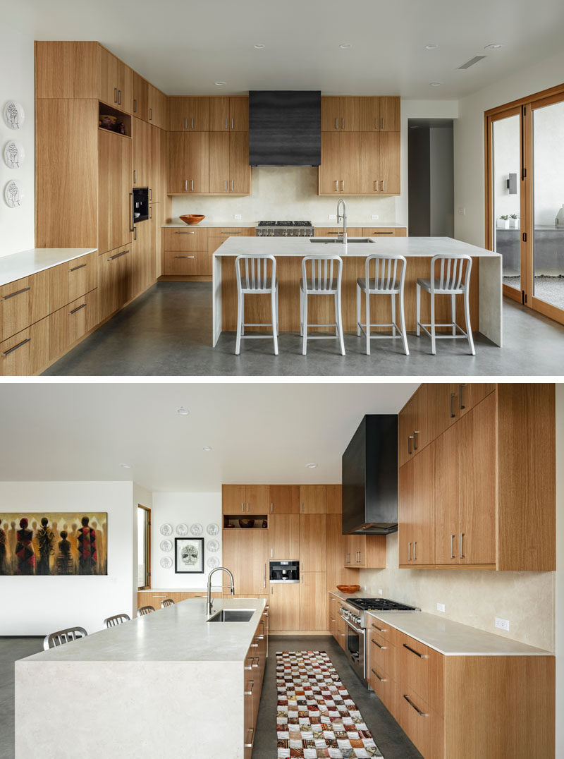 In this modern kitchen, white oak cabinetry has been paired with honed marble counters, and a custom steel hood. Bi-folding doors opens the kitchen to an outdoor space. #ModernKitchen #WoodKitchen #KitchenDesign