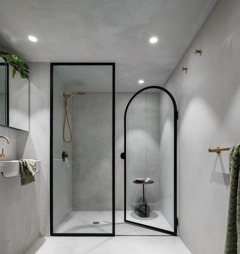 This minimalist bathroom has a black-framed glass shower screen and separate shower door. #ModernBathroom #BathroomDesign