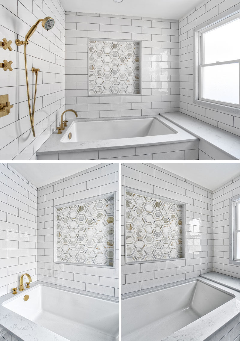 In this modern bathroom, a large undermount style soaking tub is surrounded by a Calacatta marble deck and bench. The accent tile niche breaks up the strong lines of the oversize subway tile surround, and has subtle glints of gold that pick up on the finish of the brass faucets and the hints of gold in the marble. #ModernBathroom #WhiteBathroom #UndermountBathtub #BathroomDesign