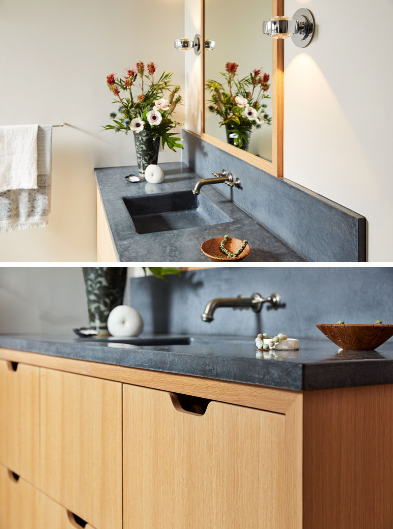 This modern master bathroom features a warm wood vanity with dark concrete counters. #BathroomVanity #Concrete #ModernBathroom