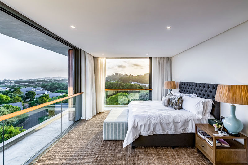 This modern master bedroom takes advantage of being high above the trees, with far-reaching views and sliding glass doors that open to allow a natural air flow, keeping the bedroom cool. #MasterBedroom #SlidingDoors