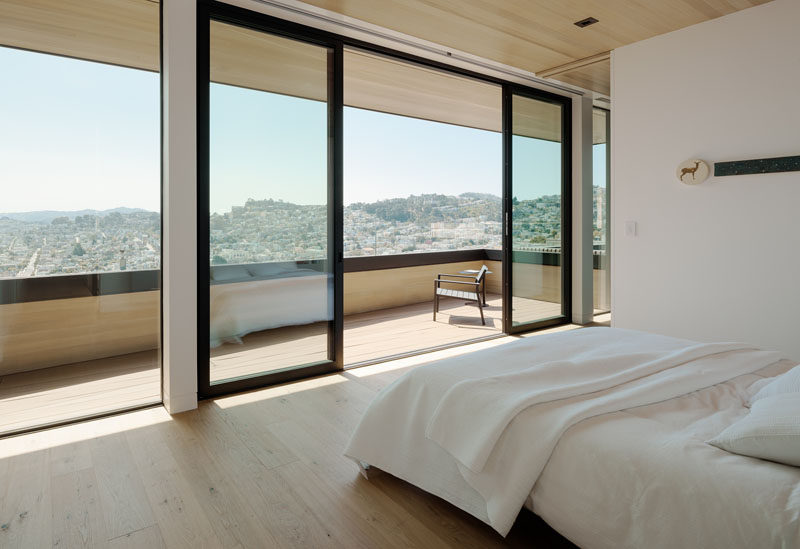 In this modern bedroom, sliding glass doors open to a covered balcony that provides views of the surrounding area. #Balcony #Bedroom #SlidingDoors