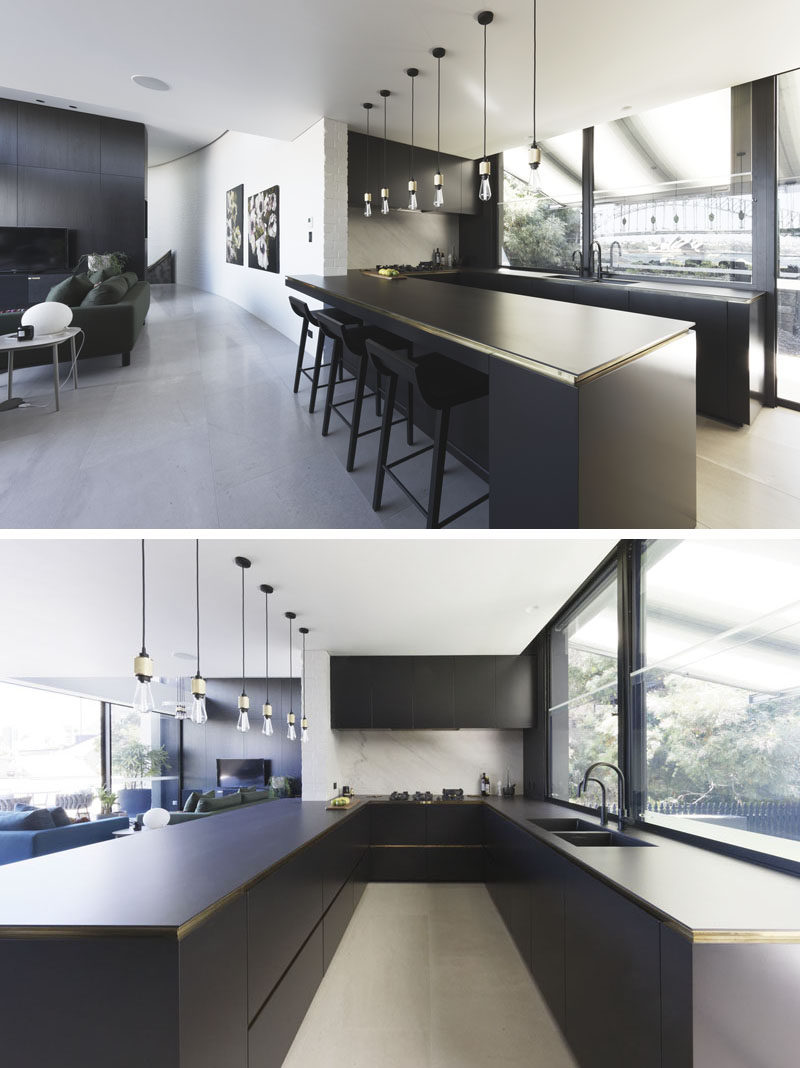 In this modern kitchen, black cabinets and dark countertops contrast the while walls and light flooring. #BlackKitchen #KitchenDesign