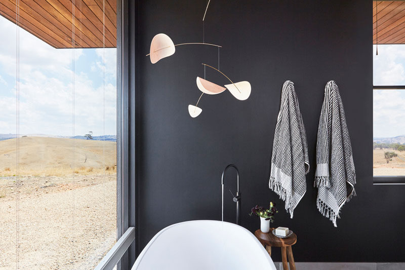 In this modern bathroom, dark walls contrast the freestanding white bathtub, and allow the natural views to be the focus of the room. #ModernBathroom #BlackBathroom