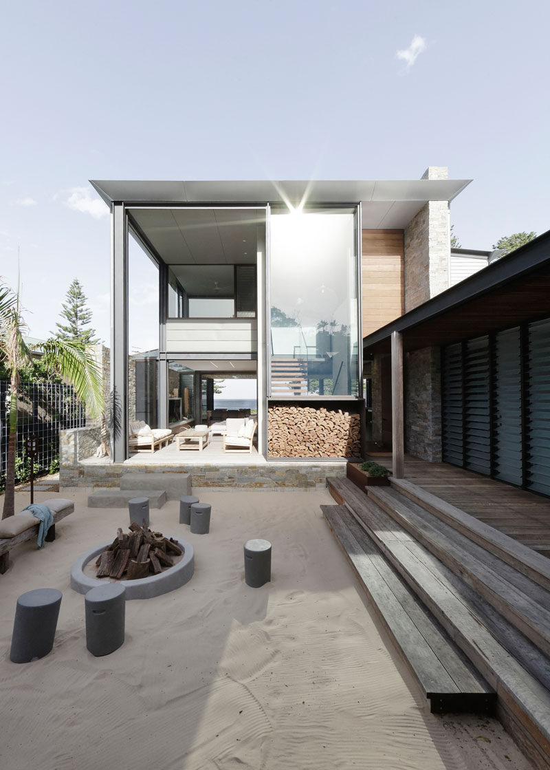 This modern house opens to a sandy courtyard with a fire pit and stool/bench seating. #Courtyard #Firepit #Landscaping #Architecture