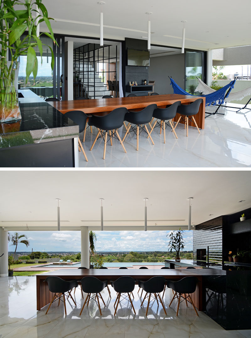 The ground floor of this modern house is dedicated to the living areas, with a covered outdoor entertaining space featuring a large wood dining table, and a black kitchen. #DiningTable #BlackKitchen