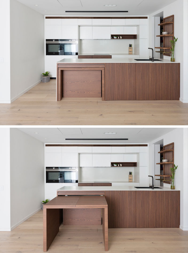 This modern kitchen features custom stained American Oak, corian countertops, and pull-out dining table, which sits flush within the kitchen bench and extends into a large dining table. #ModernKitchen #HiddenDiningTable #BuiltInDiningTable