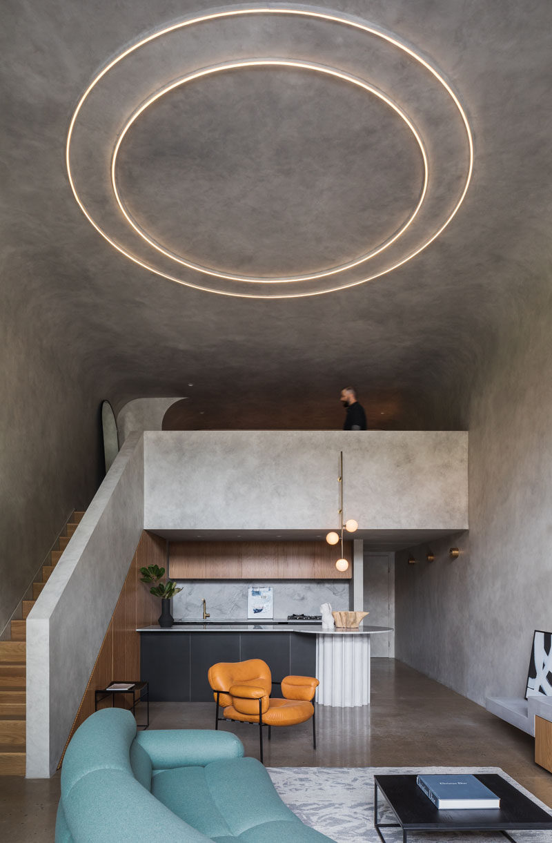 This minimalist open plan apartment features a custom kitchen and a mezzanine bedroom which overlooks the living room space and small terrace. #LoftApartment #ApartmentDesign #Kitchen