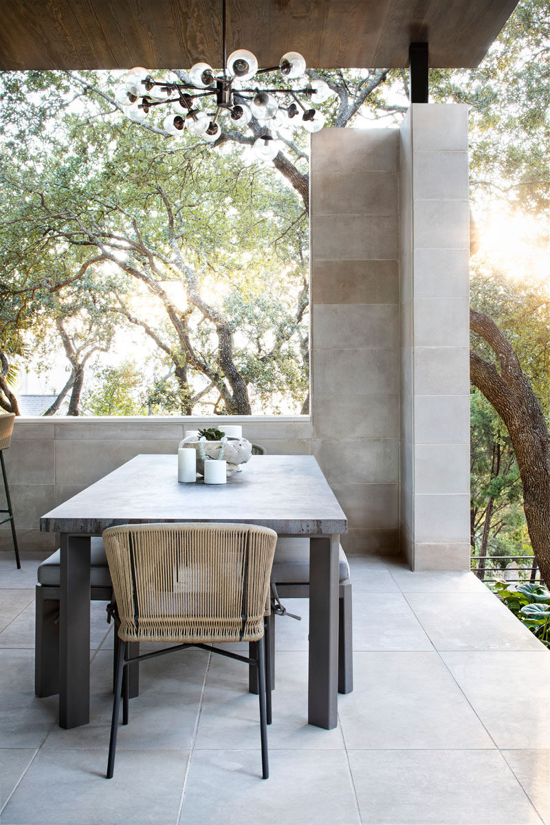 A chandelier hangs high above the alfresco dining area, while an opening in the wall provides views of the trees. #OutdoorPavilion #OutdoorDining #AlfrescoDining