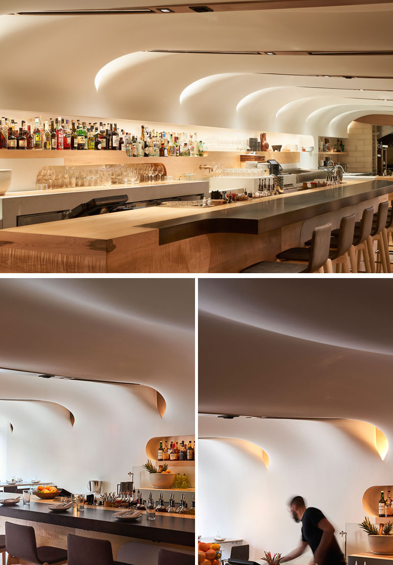 The white, undulating ceiling of this modern restaurant is composed of glass fibre-reinforced gypsum, while the bar and details feature Canadian maple and Ductal concrete. #ModernRestaurant #RestaurantDesign #InteriorDesign