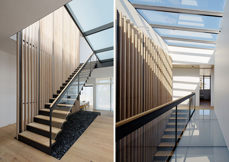 This modern bent-steel staircase runs alongside a wood slat feature and leads up to the bedrooms. A series of windows floods the stairs with natural light. #Stairs #WoodStairs #SteelStairs