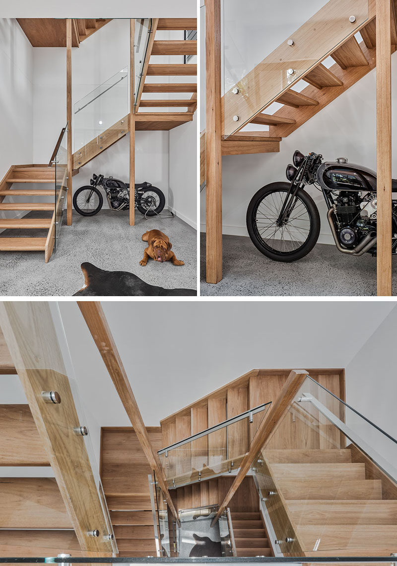 Inside this modern house, there's a wood staircase with glass handrails that lead from the garage up to the social areas of the house and bedrooms on the top floor. #ModernWoodStairs #WoodStairs