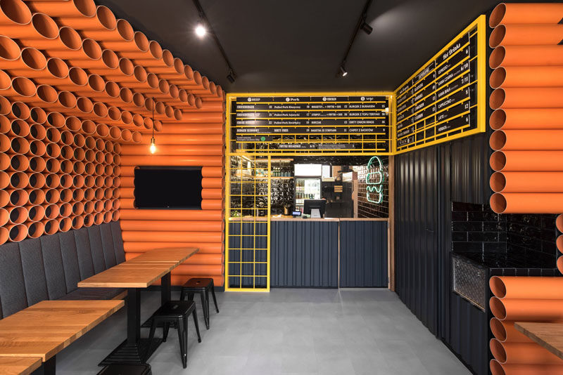 Architecture and interior design firm mode:lina, has recently completed ChiChi 4U, a modern burger restaurant in Poznan, Poland, whose interior is filled with materials that came straight from a building supplies warehouse, like orange PVC pipes and corrugated metal. #RestaurantInterior #BurgerRestaurant #InteriorDesign #ModernRestaurant