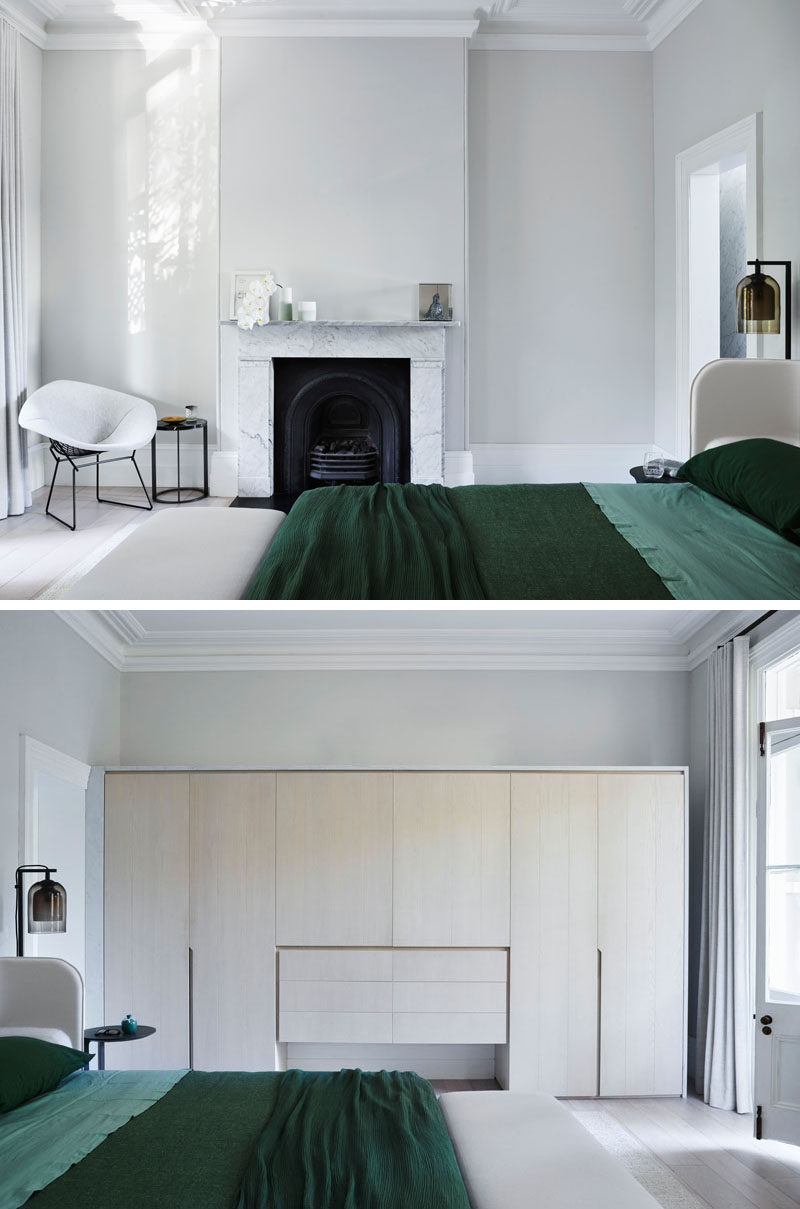 In this updated master bedroom, a wall of cabinetry in light wood provides much needed storage to the room. #MasterBedroom #Cabinets #LightWoodCabinets #Fireplace