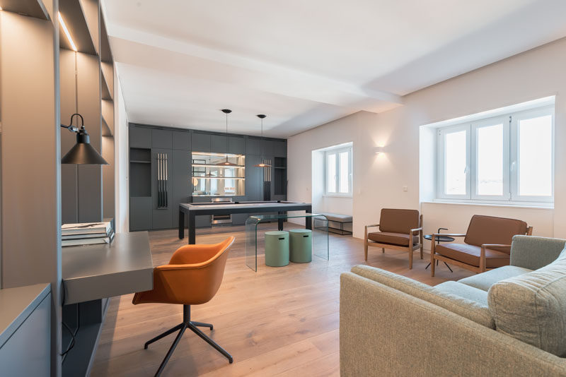 This modern apartment has a large office with a built-in desk, and a pool table that's positioned alongside a custom built-in bar. #HomeOffice #GamesRoom