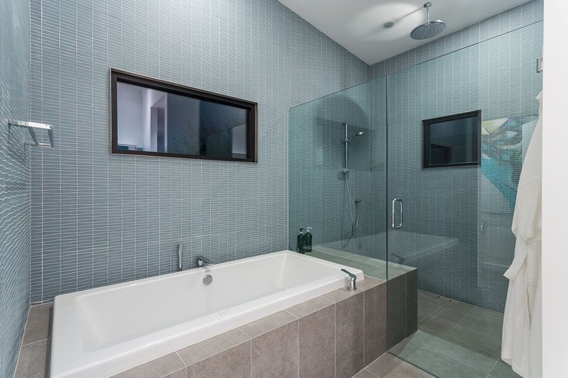 In this modern bathroom, a glass shower screen separates the shower from the built-in bath. The glass screen also allows the light from both windows to filter throughout the space. #ModernBathroom #BathroomDesign