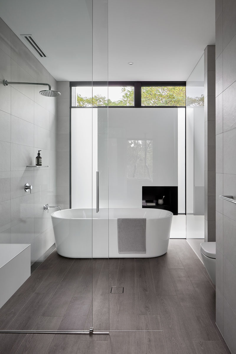 In this modern bathroom, a sliding glass door separates the shower and freestanding bath from the vanity area. #ModernBathroom #BathroomDesign