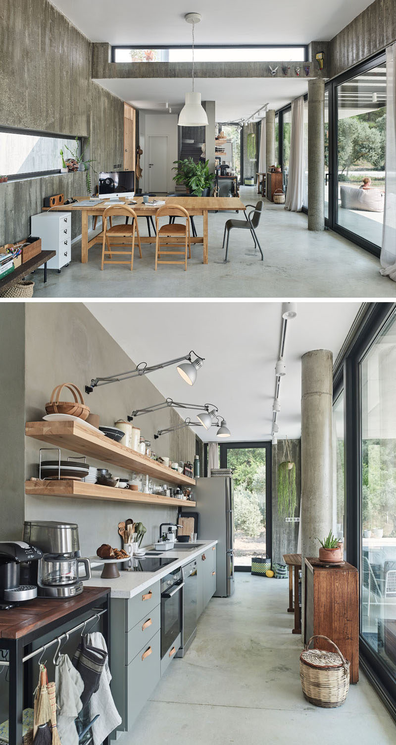 Opposite this modern kitchen, which features grey cabinets, leather hardware, and floating wood shelves, are full-height windows to provide an abundance of natural light and a view of the garden. #Kitchen #ModernKitchen #KitchenDesign