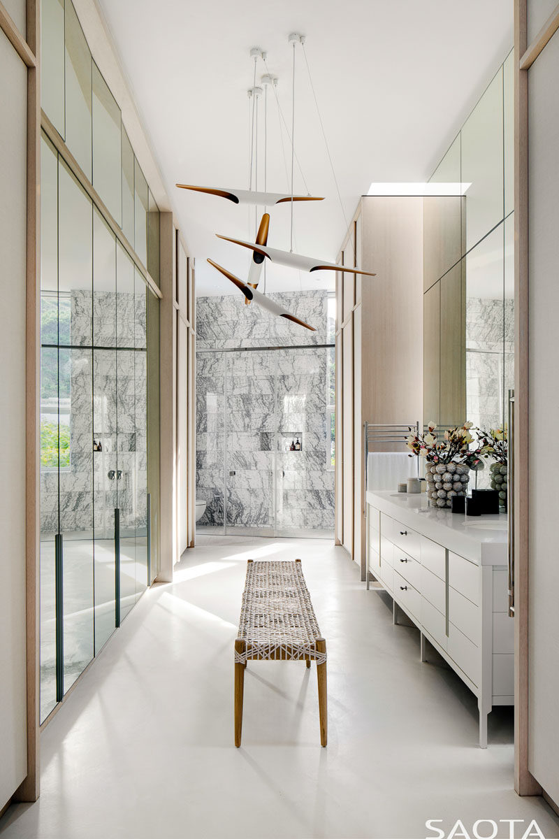 This master bathroom has a wall of mirrored wardrobes, a large vanity, and at the end is a walk-in shower, and hidden out of sight is a freestanding bathtub. #MasterBathroom #BathroomDesign