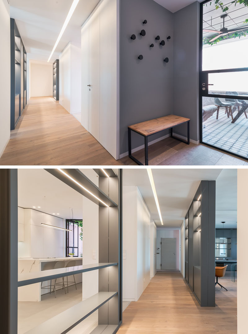 Inside this modern apartment, wood floors have been used throughout, while in the entryway, a dark grey accent wall defines an area to be used for putting on shoes, and hanging coats. #Entryway #Hallway #WoodFloors