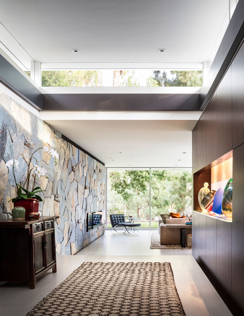 In this modern foyer, there's a Bouquet Canyon stone wall that connects with the living room. #StoneWall #Foyer #Entryway #Hallway