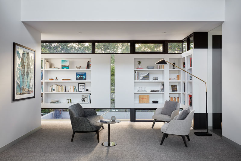 This modern house has a small library with a sitting area and built-in bookshelves. #Library #InteriorDesign #BuiltInShelving #Bookshelves