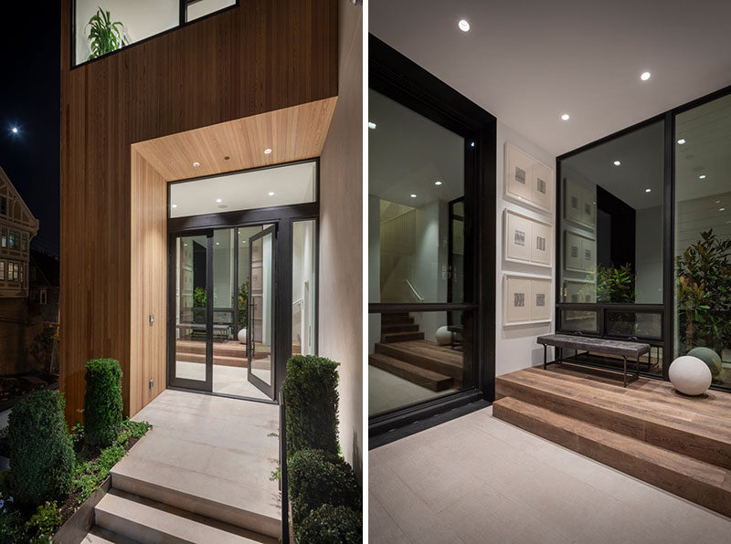 A small wood lined alcove welcomes visitors to this modern house, while just inside is a small hallway that leads to the great room. #Entryway #GlassFrontDoor