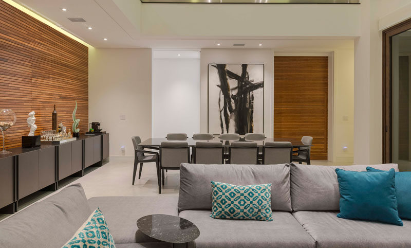 In this modern open plan interior, wood accent walls and artwork contrast the all white walls, while hidden lighting creates a calm atmosphere. #LivingRoom #DiningRoom #WoodAccentWalls