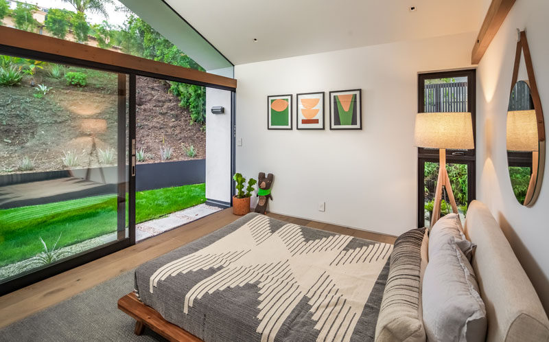 This modern bedroom has a large sliding glass door that opens to a small grassy area. #Bedroom #ModernBedroom #SlidingDoor