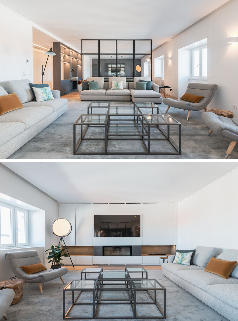 A partial wall made from black-framed glass separates the office/games room from the living room in this modern apartment. The glass wall allows the room to feel open and expansive, while the living room is focused on the fireplace and television wall the runs the width of the room. #LivingRoom #Fireplace #ModernInterior