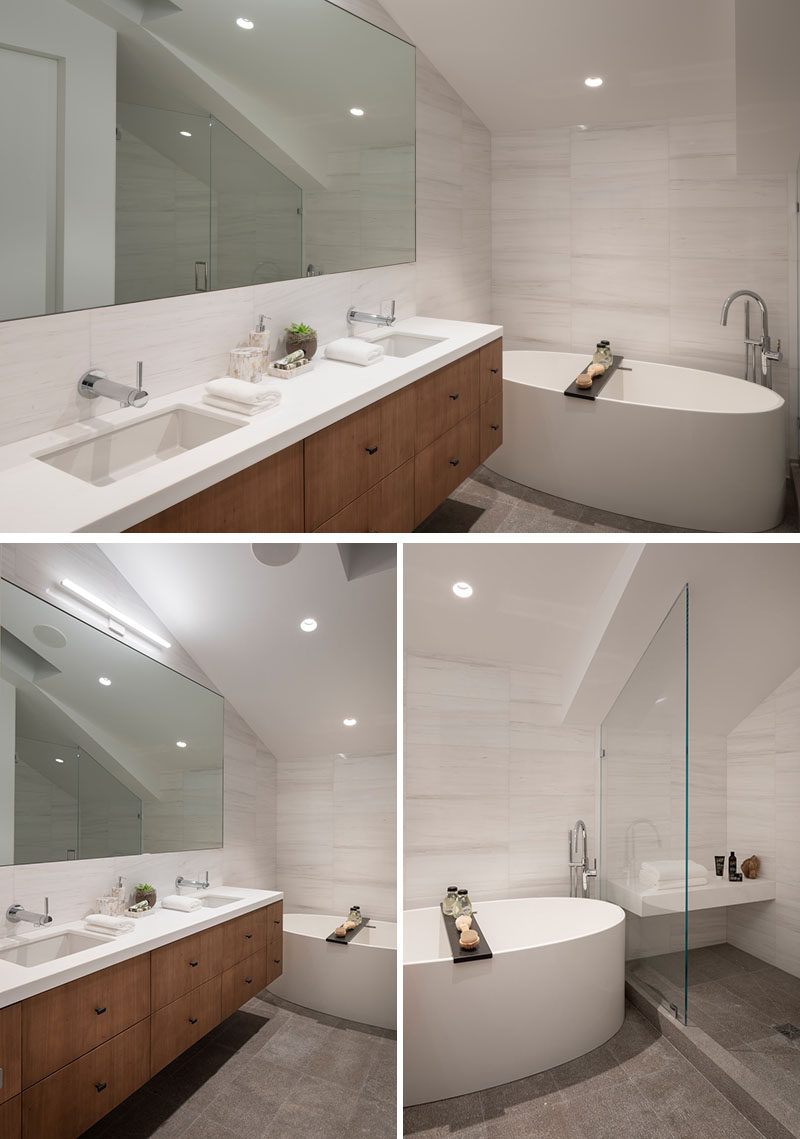 In this modern master bathroom, a large mirror reflects the light throughout the room, while the freestanding bathtub sits against the wall, and the shower is tucked away in an alcove opposite the vanity. #MasterBathroom #ModernBathroom #BathroomDesign