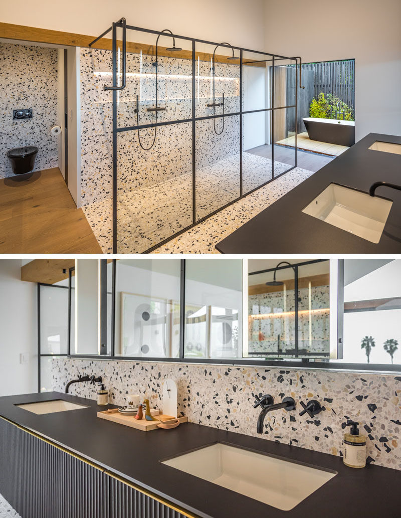 In this modern ensuite master bathroom, there's a two-person shower with a black-framed glass shower screen, while the freestanding bathtub is located outside in an area with privacy screens and plants. #ModernBathroom #EnsuiteBathroom #MasterBathroom