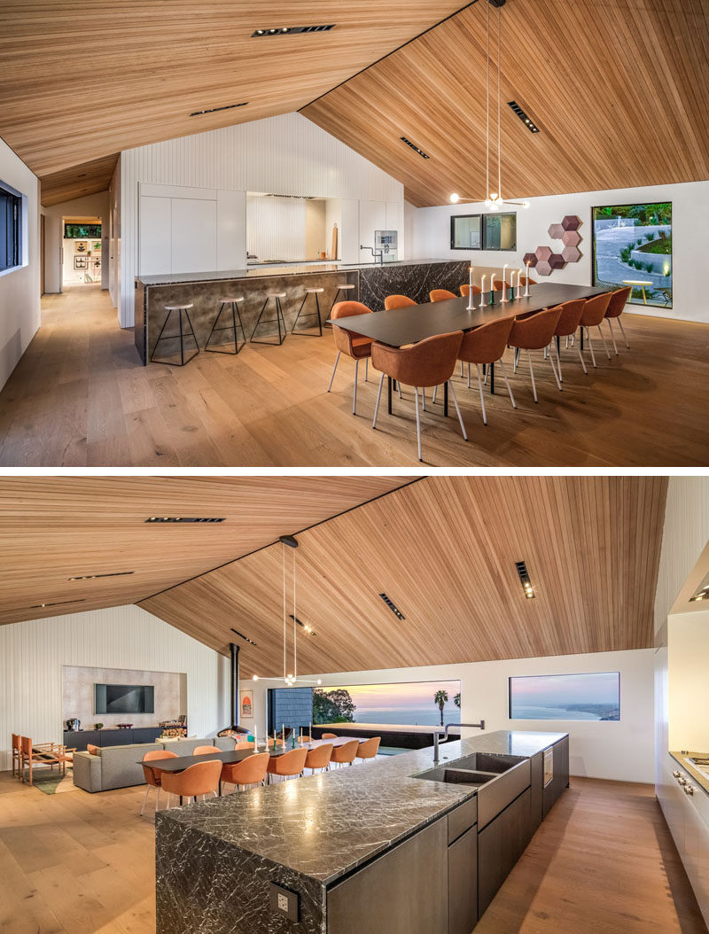 The social areas of this modern house are open plan, with the living room, dining room, and kitchen all sharing the same space. The wood ceiling helps to draw the eye upwards, and adds to the feeling of it being like a farmhouse. #ModernInterior #WoodCeiling #OpenPlanInterior