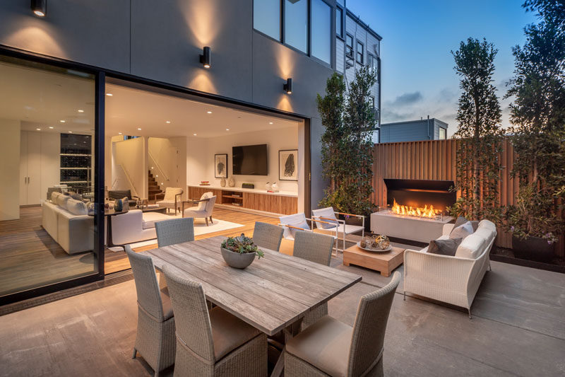 This modern patio is poised for entertaining, with an outdoor dining area and lounge. Beside the seating area is a remote controlled fireplace, creating a space that can be used during the day and into the night. #ModernPatio #OutdoorFireplace