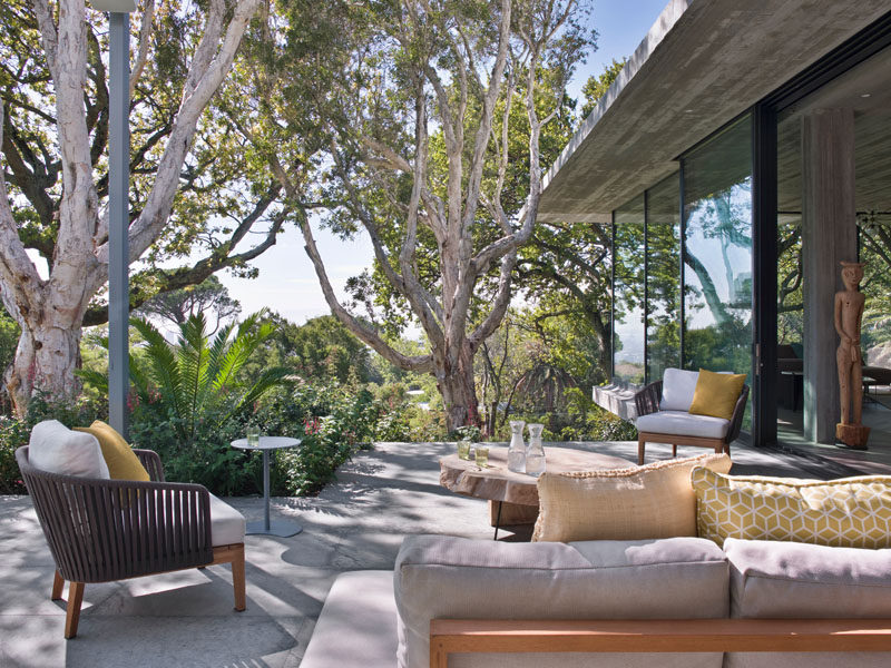 Sliding glass doors open the social areas of this modern house to a patio that take advantage of the views and mature trees that surround the property. #OutdoorSpace #ModernPatio