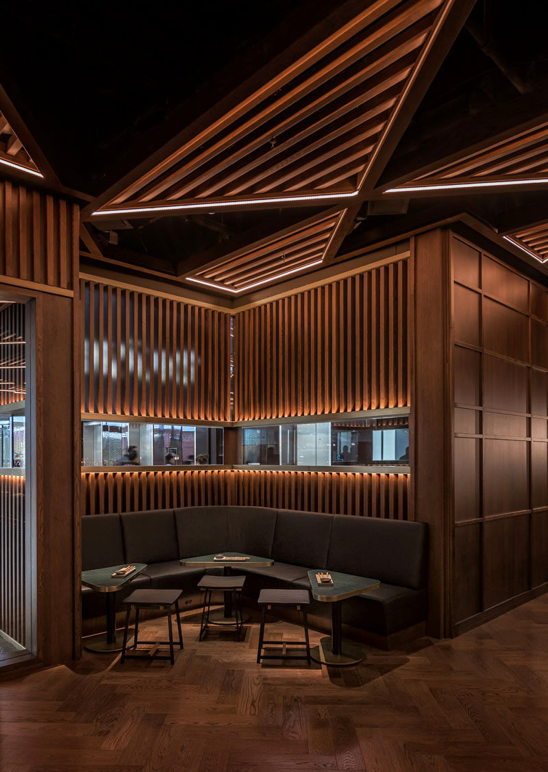 A rich palette of dark stained oak with satin brass, black metal, and textured glass detailing, greets patrons as they step inside the restaurant. #RestaurantDesign #RestaurantInterior