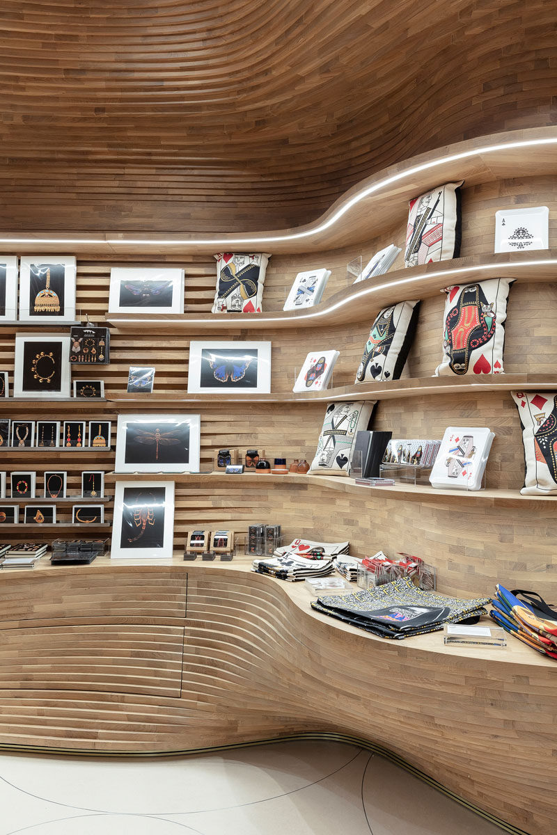 Inspired by a cave, the design of the gift shop at the National Museum of Qatar features 40,000 wood pieces that create a cave-like interior. #RetailDesign #RetailStore #ModernStore #Wood #Shelving