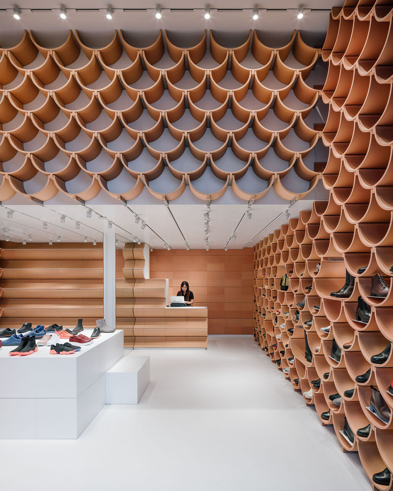Inside this modern retail store, the pattern on the walls is revealed to be made up of roof-tile like ceramic elements, that neatly complement each other. #RetailStore #StoreDesign #Ceramic #CeramicShelves