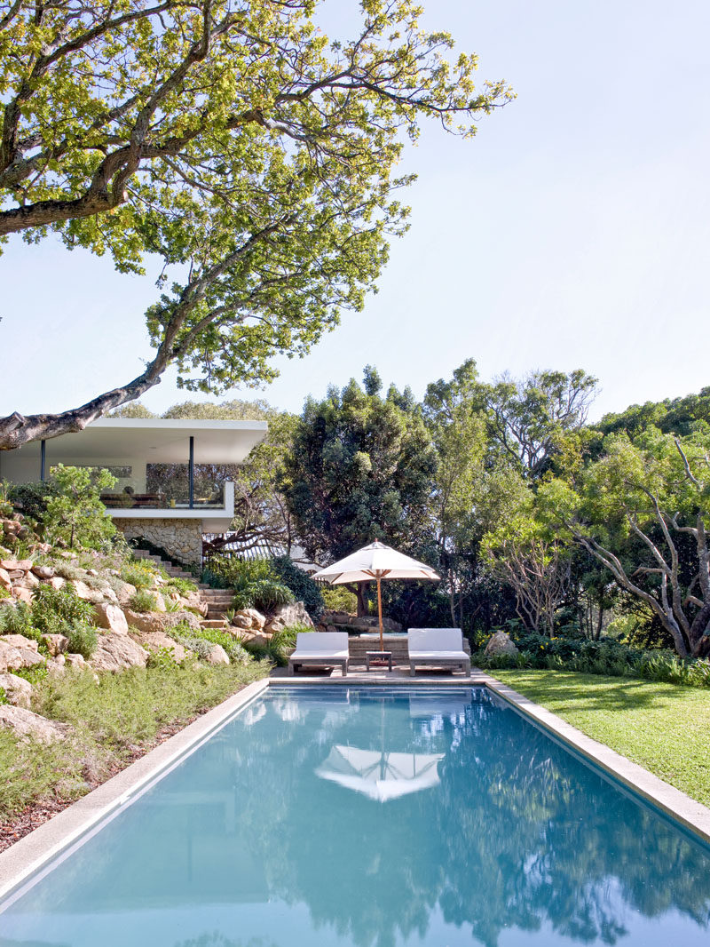 This modern house has stairs that lead from the patio, past a terraced rock garden, to the swimming pool and large grassy yard. #SwimmingPool #Landscaping