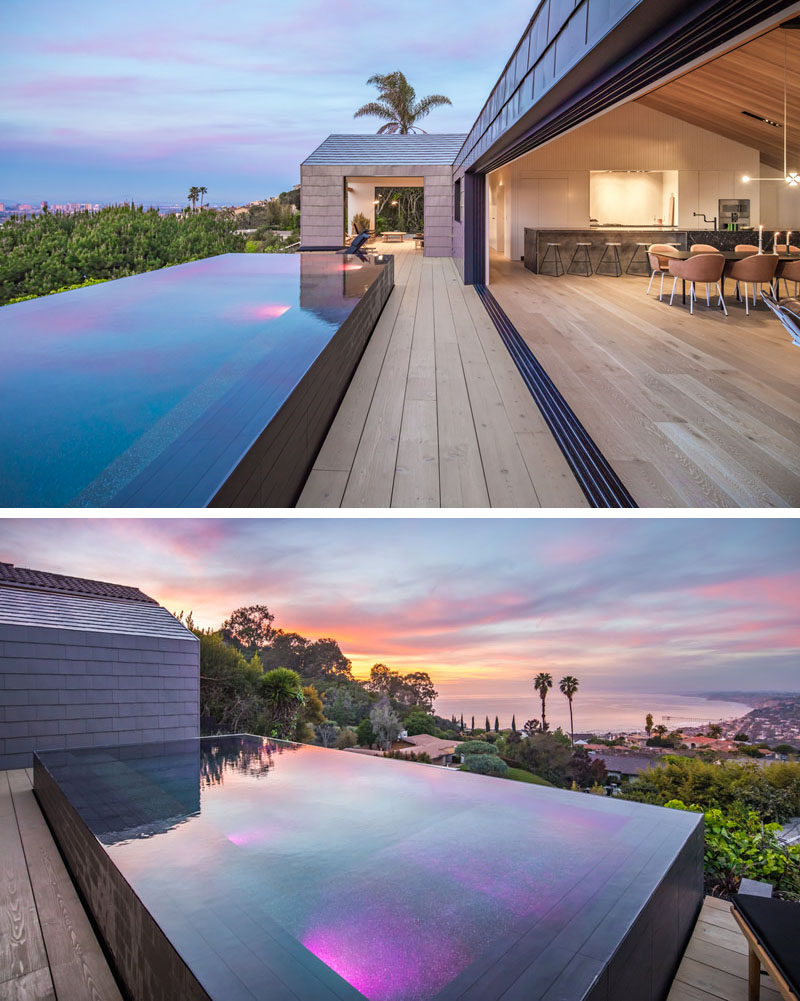 A sliding glass wall opens the social areas of this modern home to the deck and heated infinity swimming pool. #SwimmingPool #ModernHouse