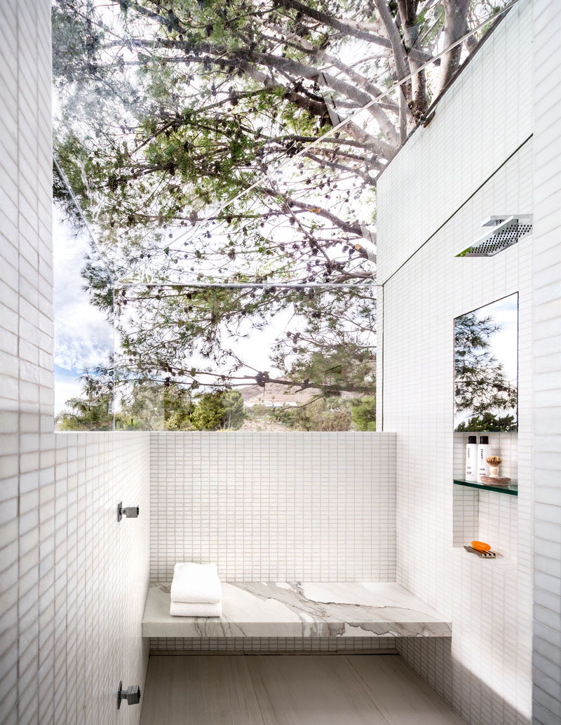 In this modern and white bathroom, a glass ceiling and partial wall in the shower provide uninterrupted views of the surrounding landscape. #ModernBathroom #Windows