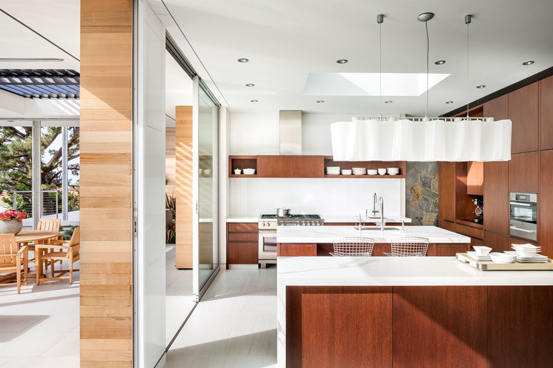 In this modern kitchen, marble countertops have been combined with stained rift white oak cabinetry, while two islands provide plenty of space for entertaining. #KitchenDesign #ModernKitchen #WoodAndWhiteKitchen