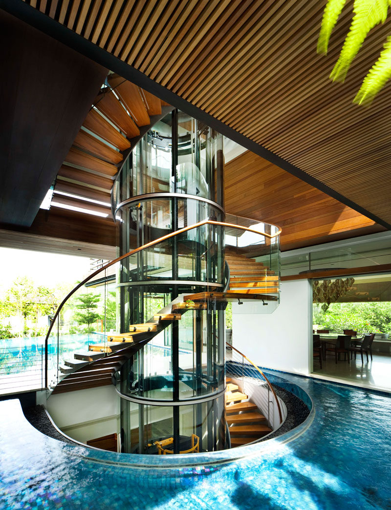 Stairs made from glass, steel, and wood, have been designed as a sculptural element in this modern house, while a wood slat ceiling and the water detail add a natural touch. #Stairs #StairDesign #WaterFeature