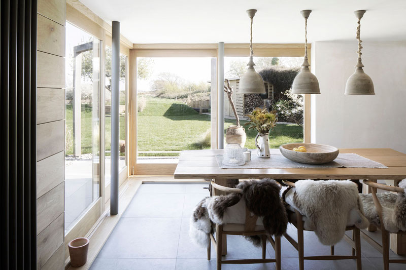 In this cottage-inspired dining room, a wood table is positioned below three pendant lights, while cushions and sheepskin adds a comfortable and warm touch to the chairs and bench. #DiningRoom #DiningRoomIdeas