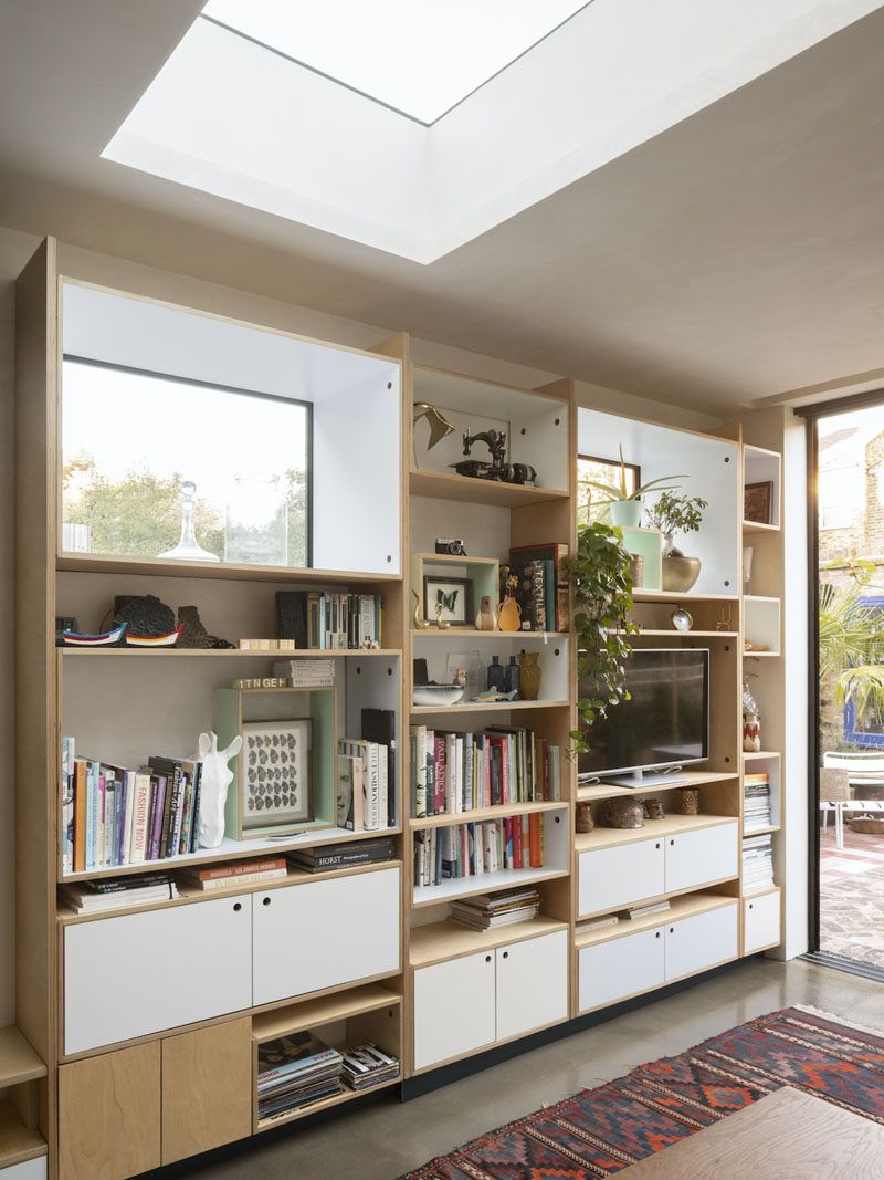 Birch plywood has been utilized for the custom shelving unit in this living room. The shelving provides ample storage, and frames both the television and the window. A skylight helps to keep the space bright. #Shelving #LivingRoom #Windows