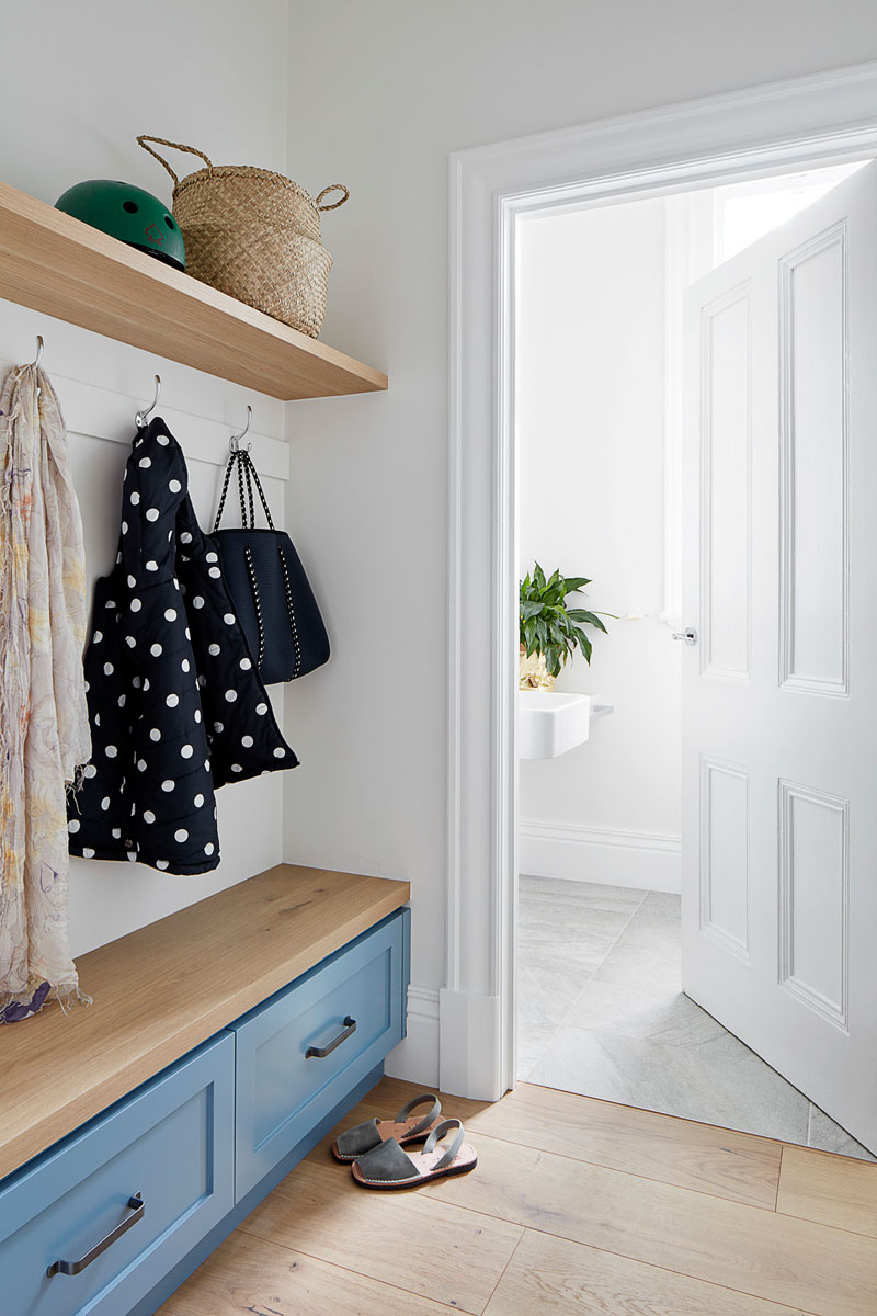 A combination of old and new is featured throughout this updated house, like in the entryway, where new built-in cabinetry and wood shelving has been added, while the door designs and trim work reference the original elements of the home. #Entryway #PowderRoom #InteriorDesign