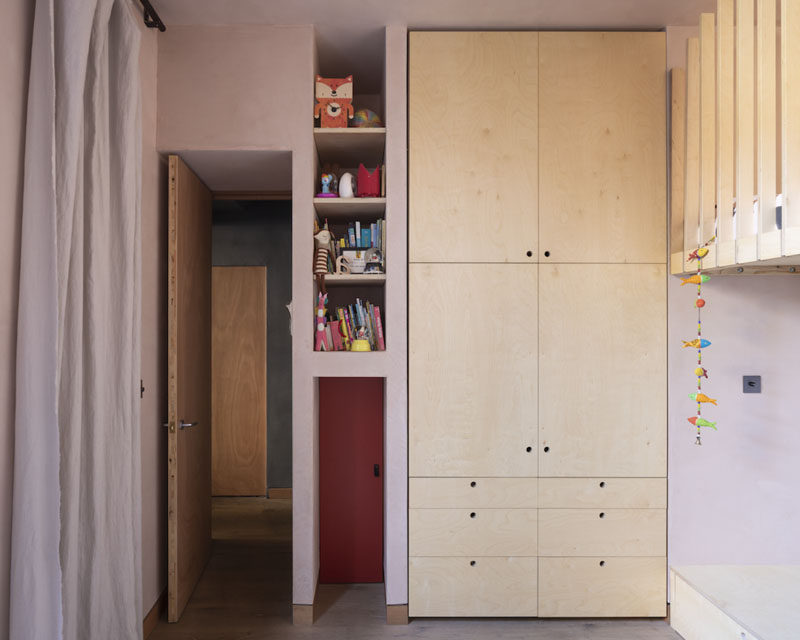 In this modern kids bedroom, a red mini-door allows the children a fun and unique way to enter their room, while built-in shelving and closets provide much needed storage. #KidsBedroom #Storage #Shelving