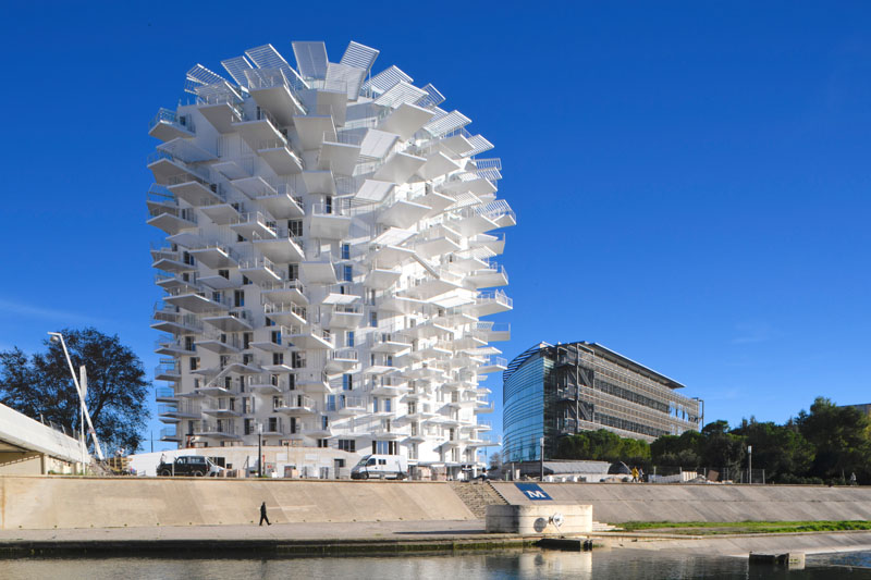 This modern apartment building in France has cantilevered balconies that surround it, while stairs connect the various outdoor spaces. #ModernArchitecture #BuildingDesign #Balconies