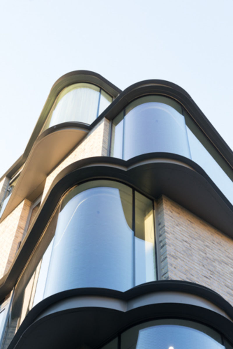 The floor-to-ceiling curved windows protruding from this modern apartment were designed to enlarge the interior living space, while also adding interest to the exterior of the building for people walking past. #Windows #CurvedWindows #ModernArchitecture