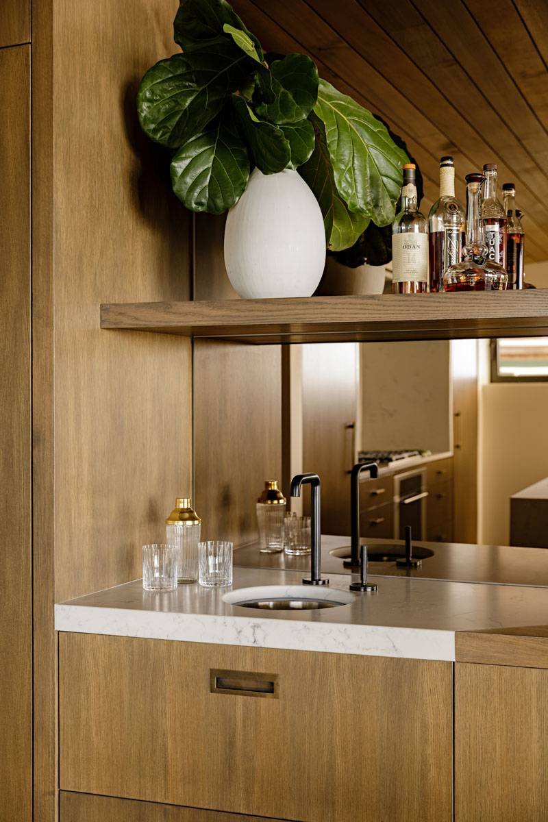 This modern bar has a mirrored backsplash that reflects the kitchen. #MirroredBacksplash #HomeBar #Bar